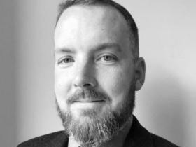 Black and white headshot of Dr David Campbell, who has short dark hear and a beard