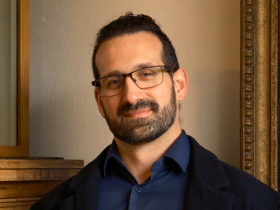 Dr Fernando Messore, who has dark tied-back hair and glasses, wearing a dark blue shirt and black jacket