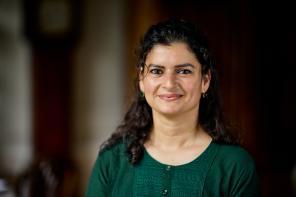 Photo of Aliya Khalid, who has long dark wavy hair and is wearing a green top