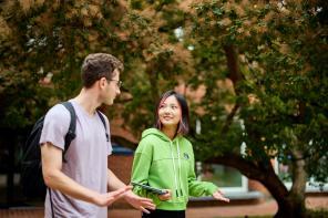 A male student and a female student walking outside talking to one another