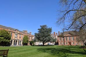 Red brick buildings surrounded by trees and grass