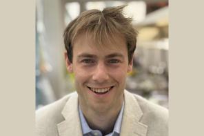 Thibault Rushbrookm who has short sandy brown hair and is wearing a pale coloured suit, smiles at the camera