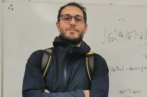 Andrea Medraglia standing in front of a whiteboard with mathematical problems