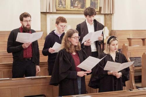 Five students in the LMH Choir singing in the Chapel pews.