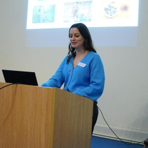 Jasmin Willis, wearing a blue jumper, giving a presentation at a conference