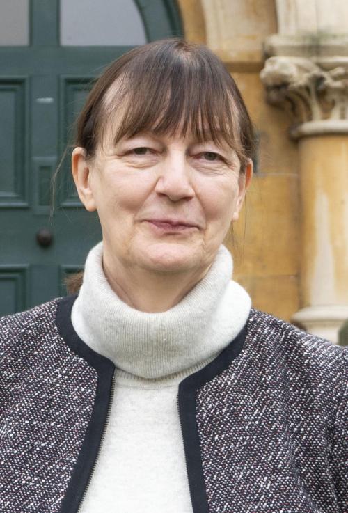 Dr Margaret Coombe standing outside Old Old Hall at LMH