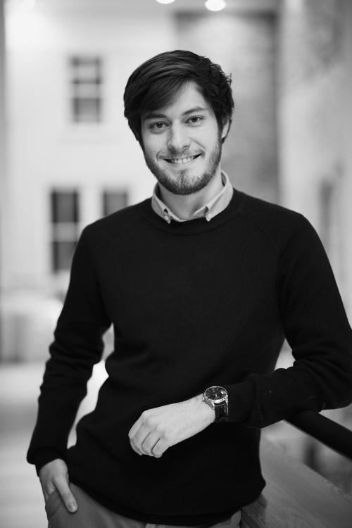 Alex leaning against a railing, smiling at the camera