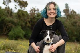 Photo of Edith Matthewson, who has shoulder length blue hair and her dog in a field