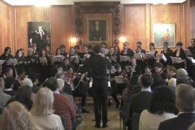 A choir dressed all in black performing in a wood-panelled room