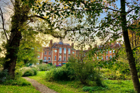 A photo of a red brick building peeping out through some trees