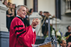 Professor Stephen Blyth in a red academic gown speaking in the Sheldonian