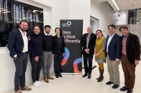 A group of men and women stand in a line. Between them a banner reads 'Cancer Grand Challenges: Dare to think differently'
