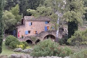 An old stone house sit nestled in hill surrounded by trees