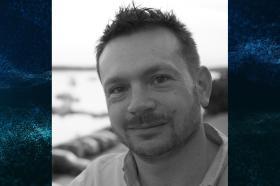 A black and white photo of Professor Alan Barr, who has short dark hair and stubble