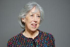 Baroness Manningham-Buller, an older woman with grey hair, wearing a colourful textured jacket, smiling against a plain grey background
