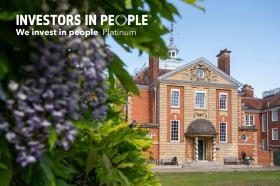 A photo of LMH's Talbot Hall, an imposing red brick building, with purple wisteria in the foreground. The Investors in People Platinum logo is visible on the photograph