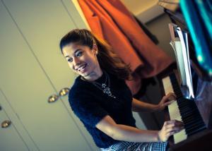 A young woman playing the piano and laughing