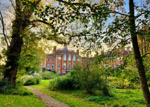 A photo of a red brick building peeping out through some trees