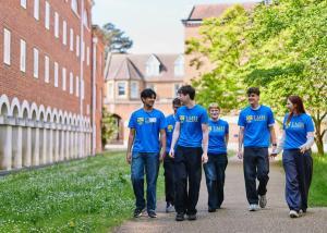 A group of students in blue tshirts walking through the grounds of Lady Margaret Hall