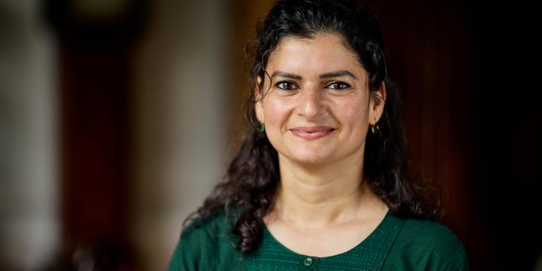 Photo of Aliya Khalid, who has long dark wavy hair and is wearing a green top