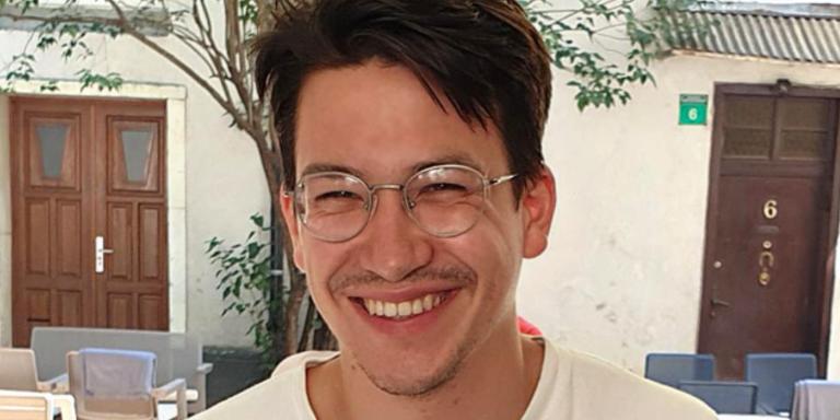 Fabian Helmrich, who has dark hair and glasses, sitting at a cafe table