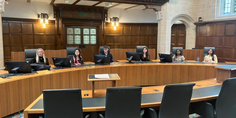 A photo of six students sitting at chairs at the UK High Court