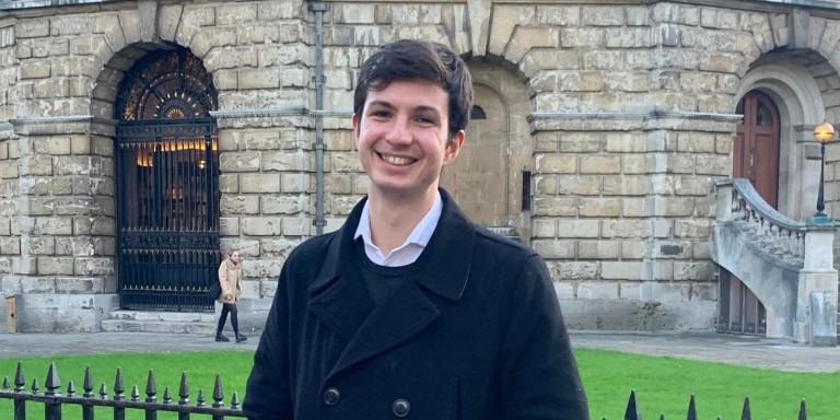 Photo of Oliver Neely standing in front of the Radcliffe Camera in Oxford