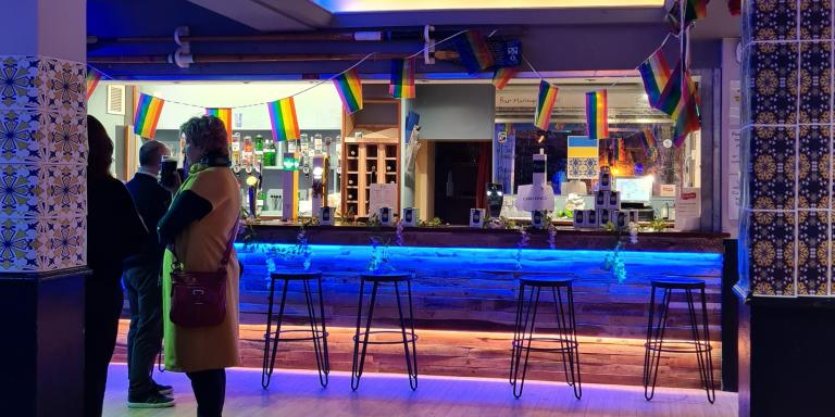 Photo of people standing in a bar with blue lighting