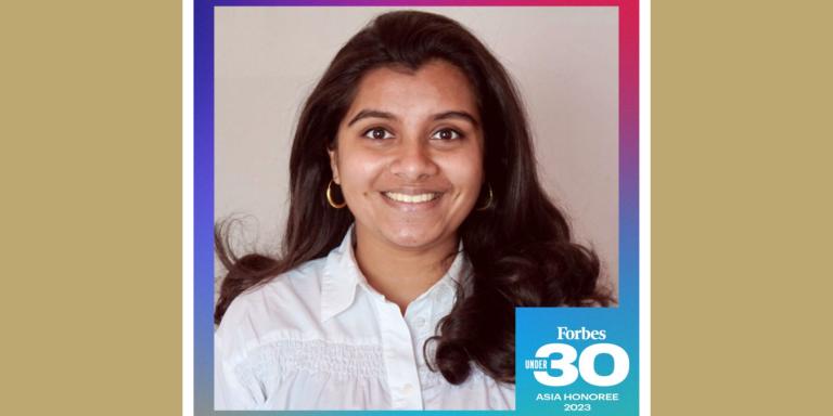 Vishnupriya Rajgarhia, an Indian woman with long dark brown hair and brown eyes, smiling at the camera