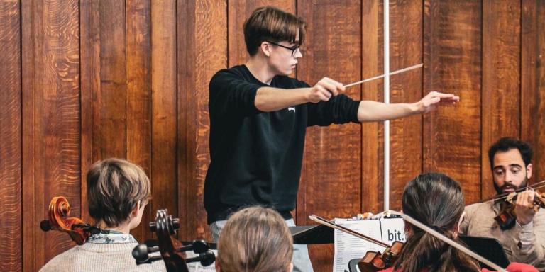 Felix Kirkby conducting a group of orchestral musicians
