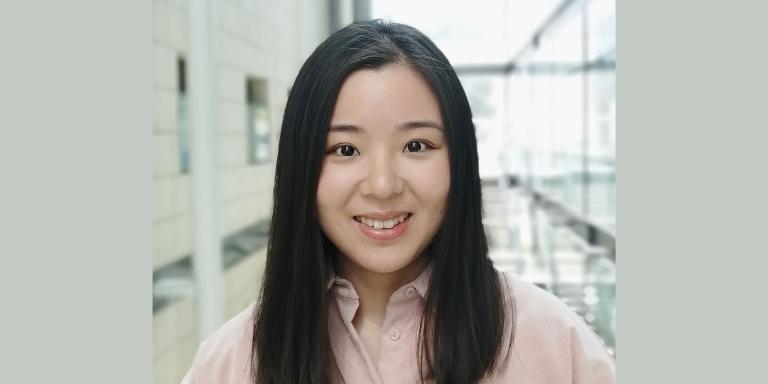 Yujia Qing standing in a brightly lit atrium