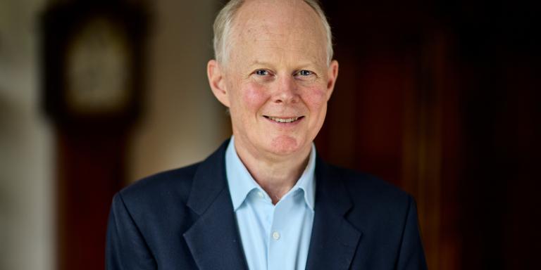 Photo of Andrew Macdonald, who is wearing a dark blue suit with a light blue shirt