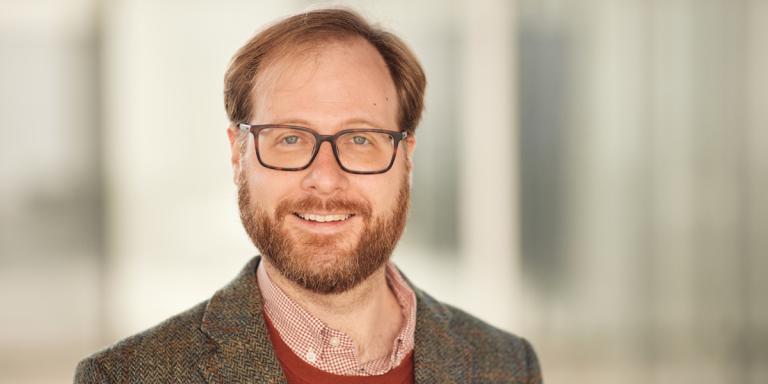 Frank DiTraglia, who has short red-brown hair, a beard and glasses