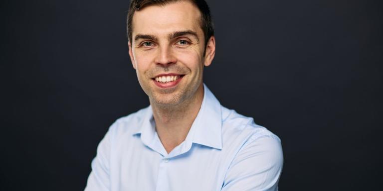 Dr Maximilian Fitz-James wearing a pale blue shirt and smiling at the camera