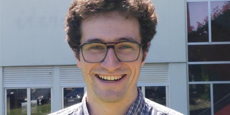 Pablo Bilbao, who has short dark brown hair and glasses, standing in front of a building with lots of windows