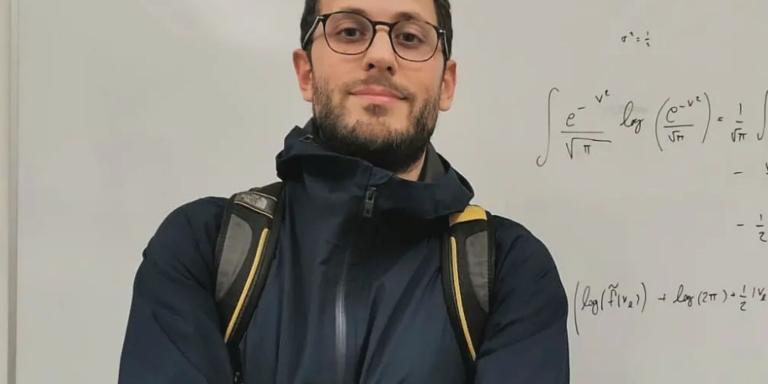 Andrea Medraglia standing in front of a whiteboard with mathematical problems