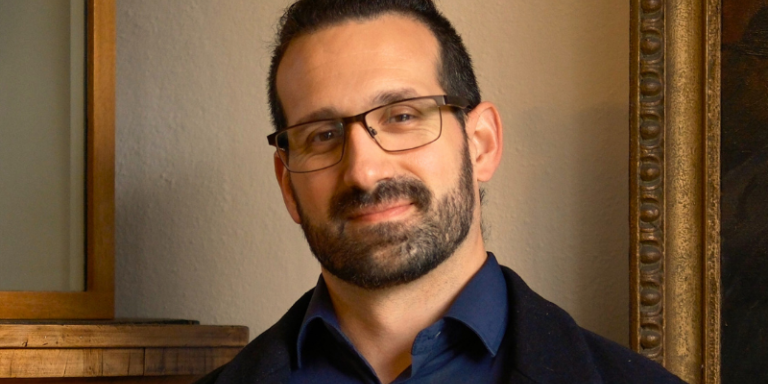 Dr Fernando Messore, who has dark tied-back hair and glasses, wearing a dark blue shirt and black jacket