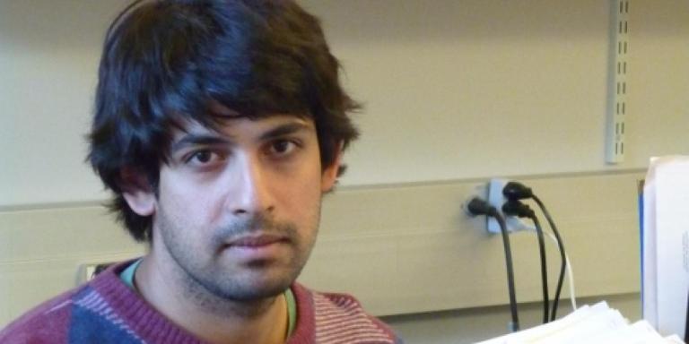 Varun Kanade, who is wearing a jumper in different shades of purple and has dark hair, sitting in an office