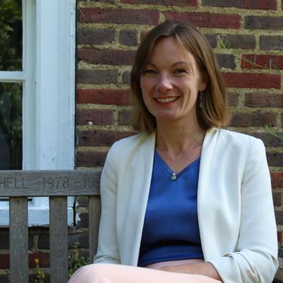 Anna Bates, a white woman with shoulder-length brown hair wearing a white jacket