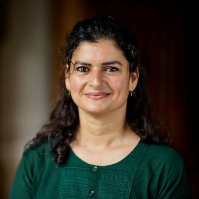 Photo of Aliya Khalid, who has long dark wavy hair and is wearing a green top