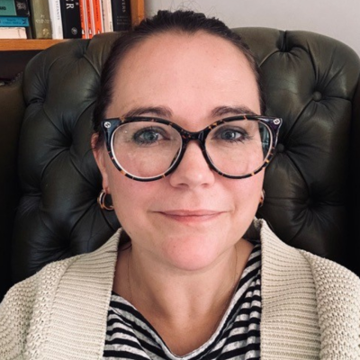 Dr Sophie Nicholls, who has dark brown hair tied back in a ponytail and dark-framed glasses, sitting in her office