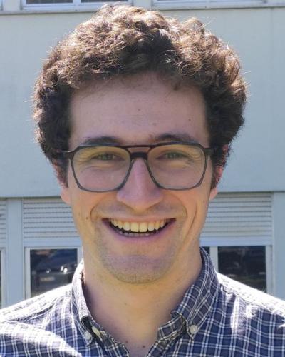 Dr Pablo Bilbao, who has dark curly brown hair and dark-rimmed glasses smiles widely at the camera