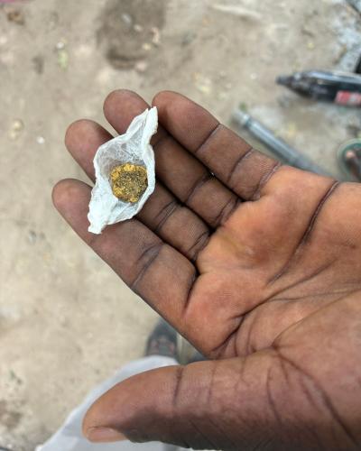 A hand holding a gold nugget