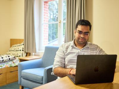 A male graduate student sitting in their student accommodation