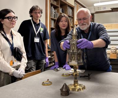 A curator lifts the lid from a 19th-c golden monstrance in a private teaching room in the Ashmolean while LMH students look on