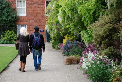 Two students walking away from the camera, on a gravel path in a garden. 