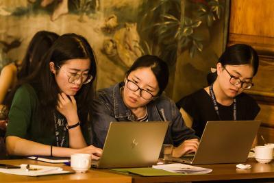 Three students working together, looking intently at a laptop screen.