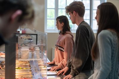 Students standing in a line waiting to be served food in a canteen