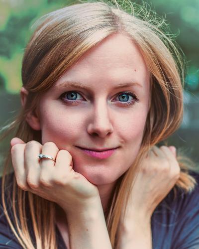 Close-up of Lauren Johnson, who has long blonde hair and is looking into the camera with her chin resting on her hands