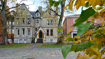 An old Victorian building seen through a screen of leaves tinged with autumn colour